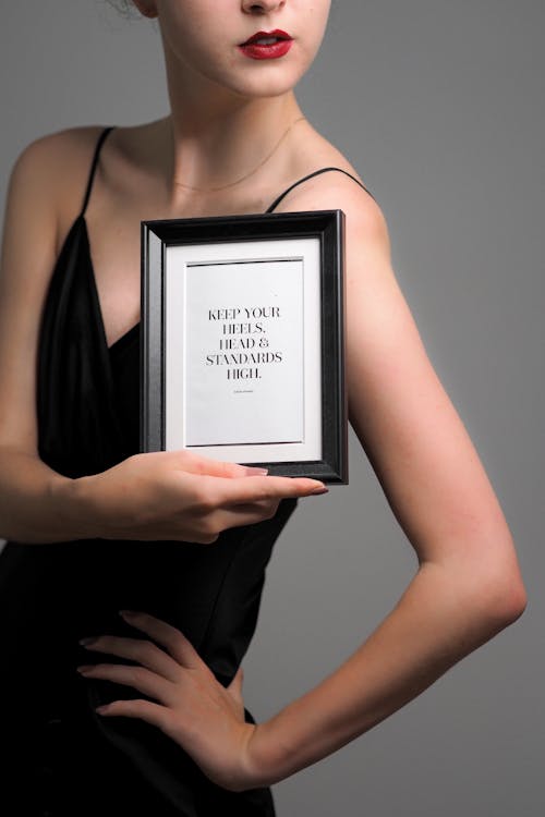 A woman holding a picture frame with the words, you are beautiful
