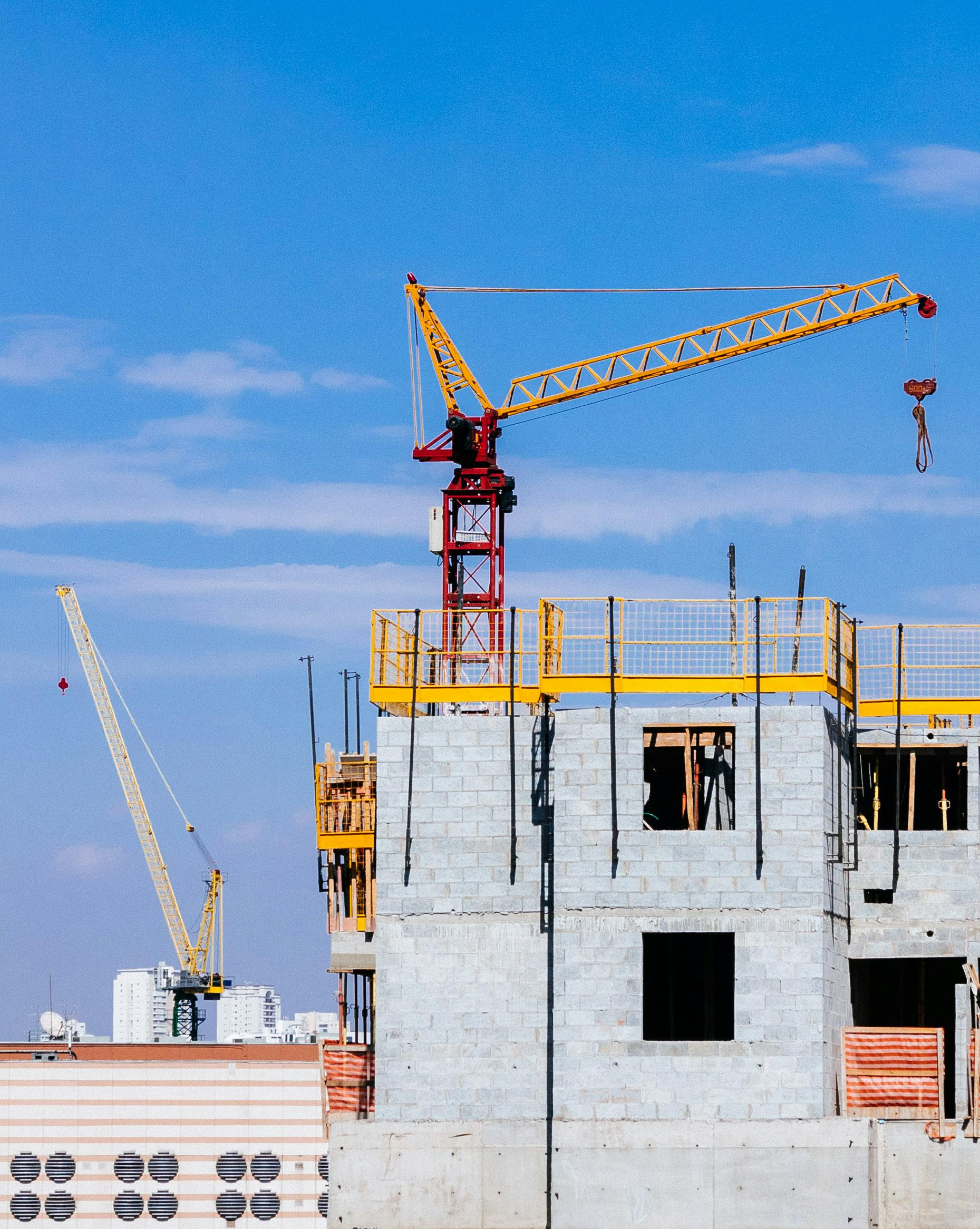 red and yellow tower crane on top of building under construction