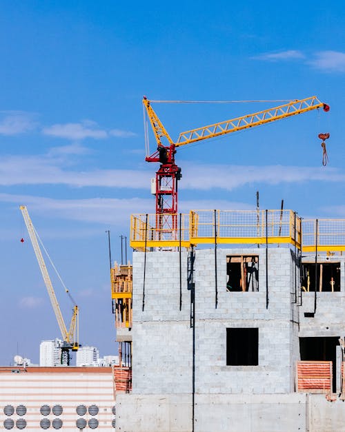 Free Red and Yellow Tower Crane on Top of Building Under Construction Stock Photo