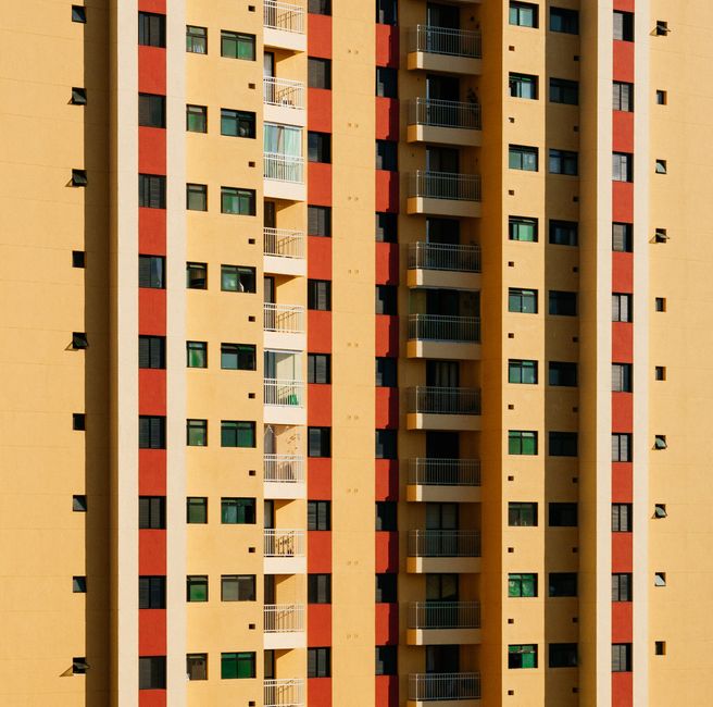 Close-up view of a contemporary high-rise building facade featuring a pattern of balconies and colorful panels.
