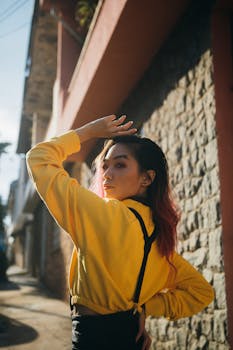 身着亮黄色夹克的时尚女性在户外摆出造型，尽显都市风尚