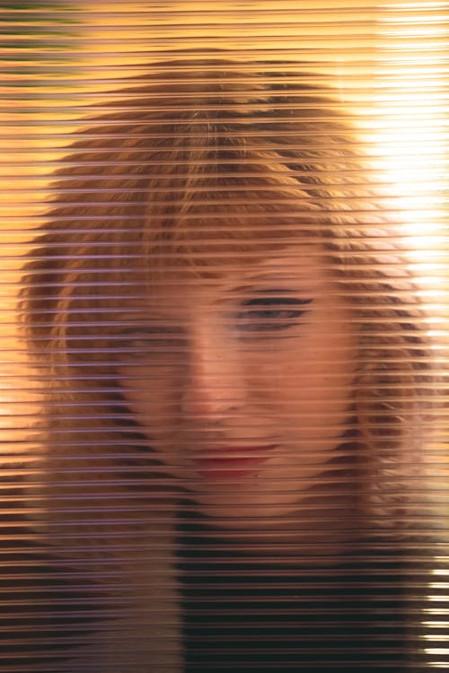 Woman in Black Shirt Behind Glass Window With Blinds