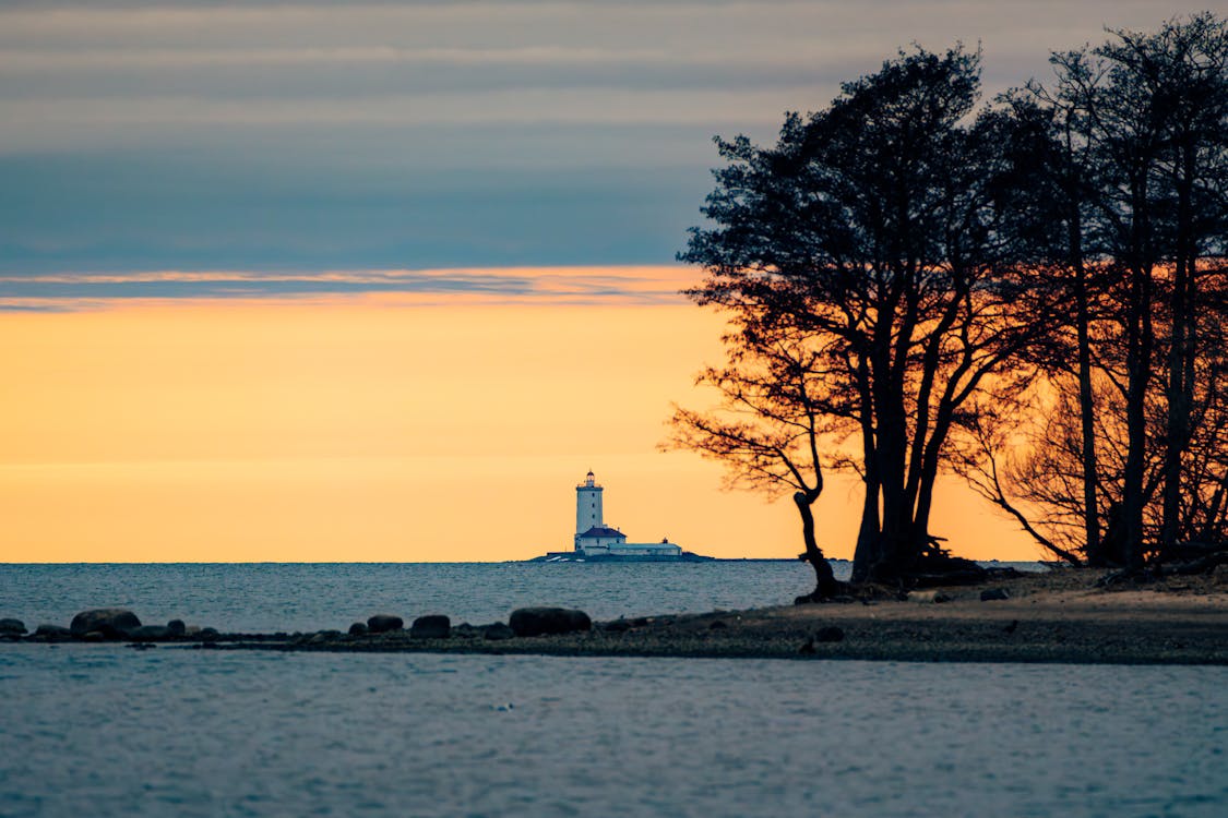 A lighthouse is seen in the distance at sunset
