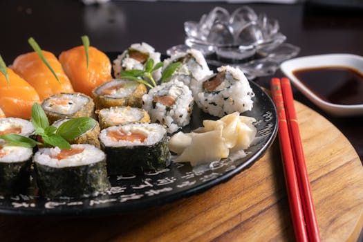 A mouth-watering assortment of sushi served with soy sauce, garnished with fresh herbs, and chopsticks on a wooden board.
