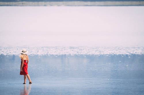 Woman in Red Tube Dress and White Hat Walking in Beach