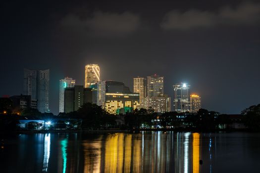 Illuminated skyline reflecting on water at night, showcasing modern architecture.