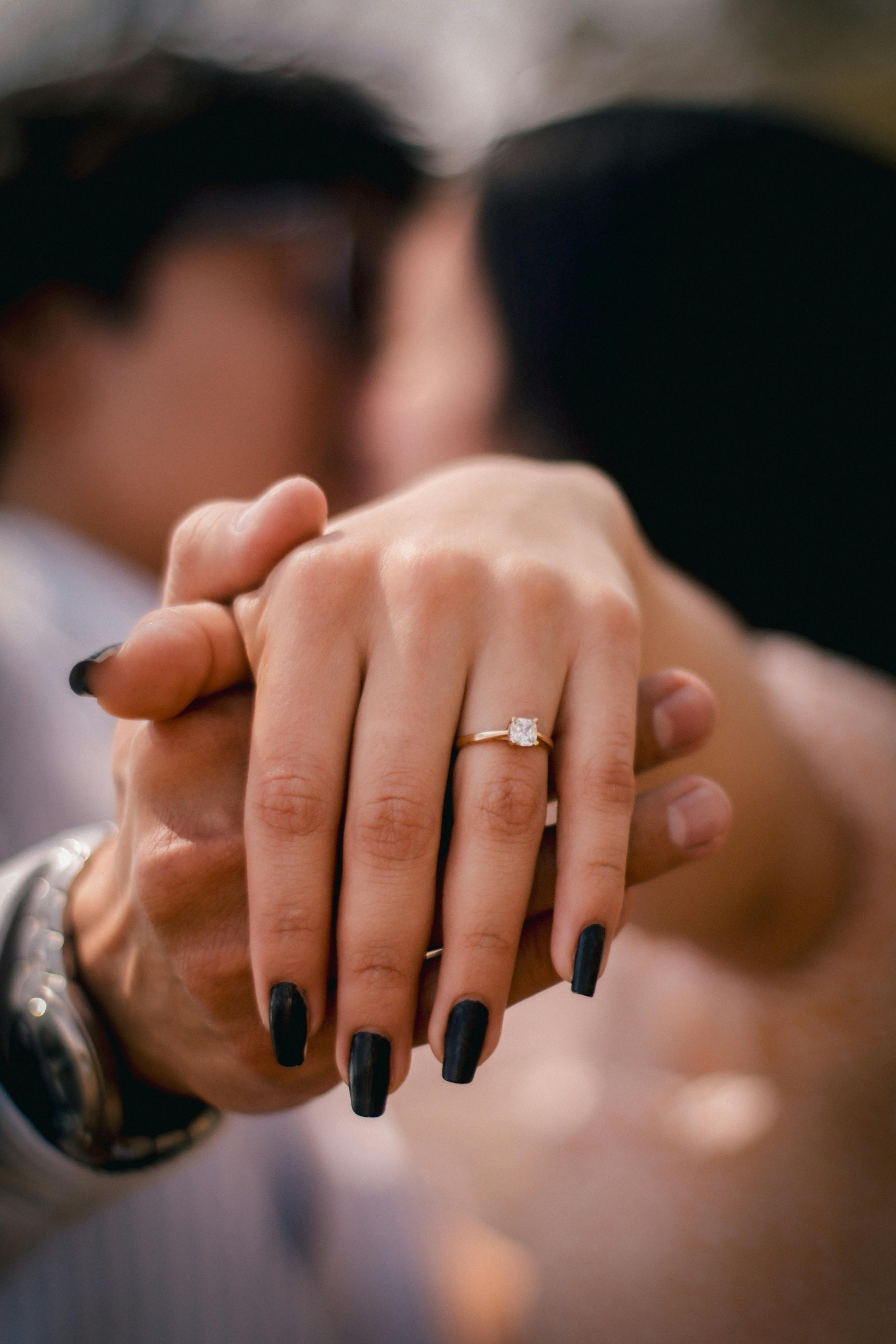 Free Close-up of a couple holding hands, showcasing an engagement ring. Stock Photo