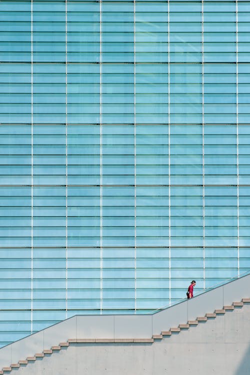 A person walking down the stairs in front of a large glass building