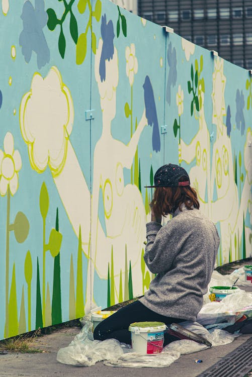 A woman painting a mural on a wall