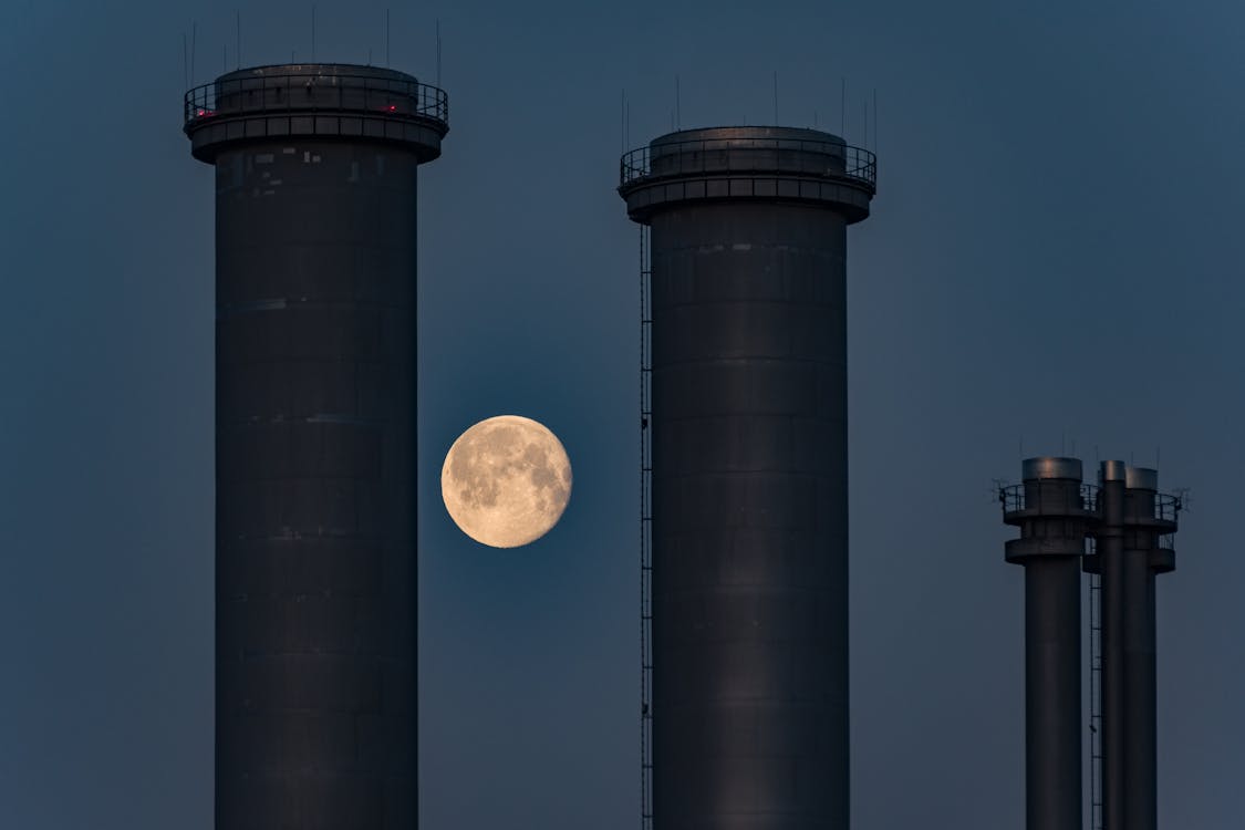 The moon rises over the chimneys of a power plant