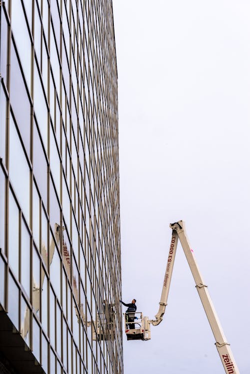 A man on a cherry picker is working on a building