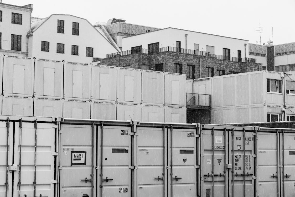 Black and white photo of containers in front of buildings