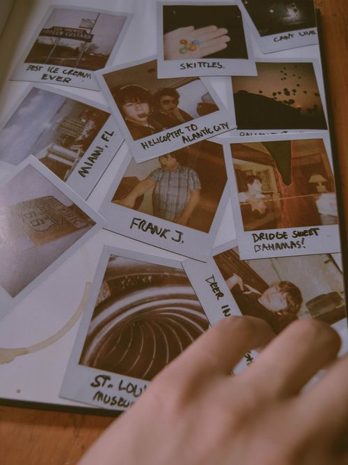 Free A close-up of a hand flipping through a vintage Polaroid photo album. Stock Photo