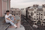 年轻人坐在屋顶上，俯瞰着城市中具有历史感的建筑街道