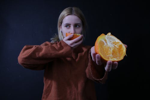 オレンジ色の柑橘系の果物を保持している女性
