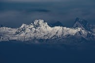 白雪覆盖的山脉在变幻的天空下巍然耸立，壮丽非凡，令人叹为观止