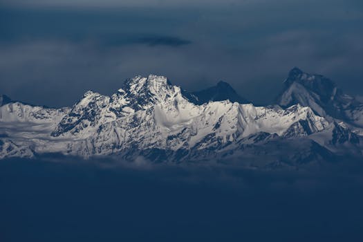 Breathtaking snow-covered mountains rising majestically under a moody sky, displaying nature's grandeur.