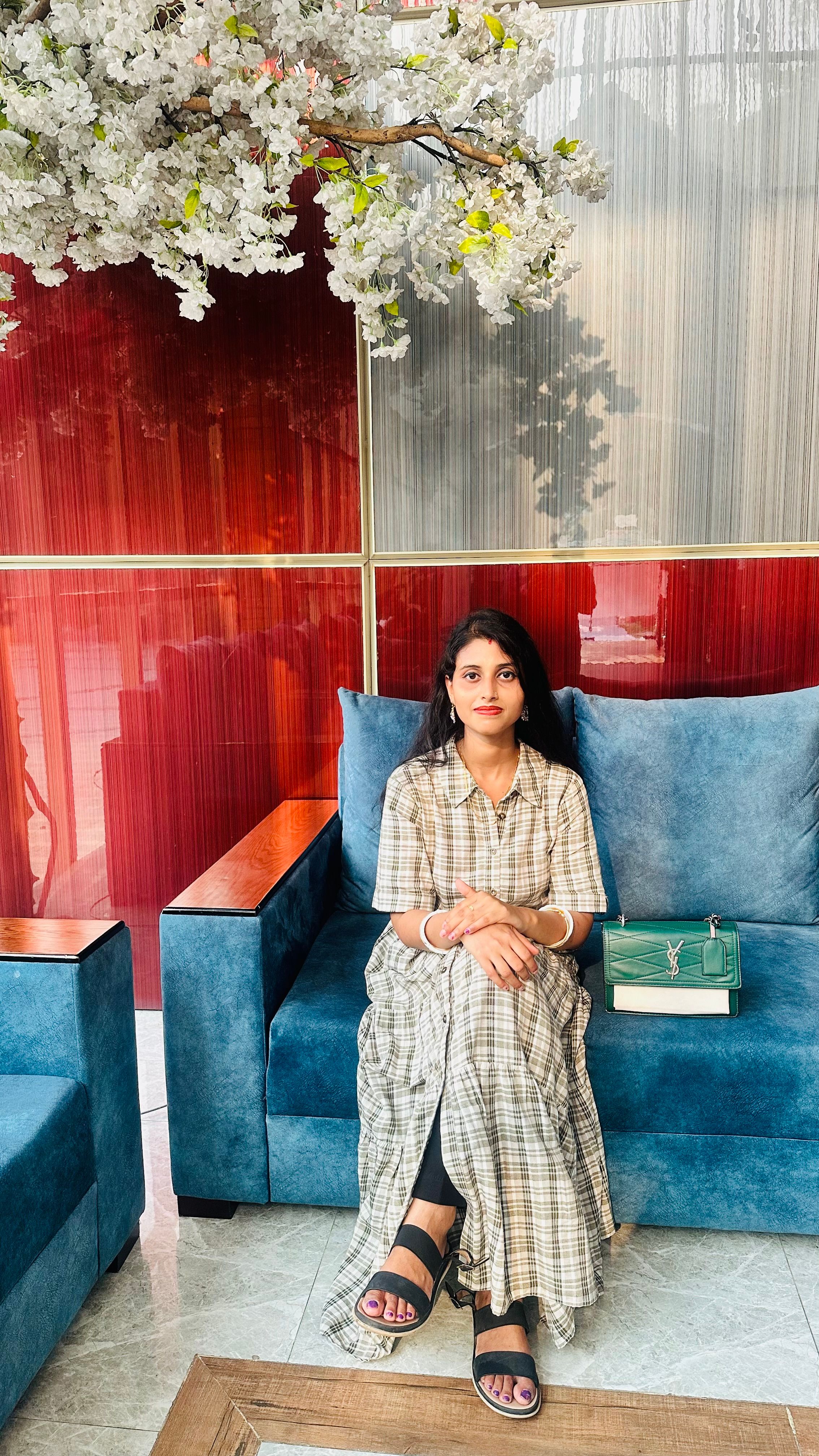 Fotomural Una mujer sentada en un sofá azul bajo flores blancas decorativas en el interior.