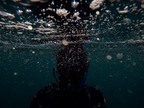 Diver silhouette with bubbles underwater captured in motion, showcasing aquatic exploration.