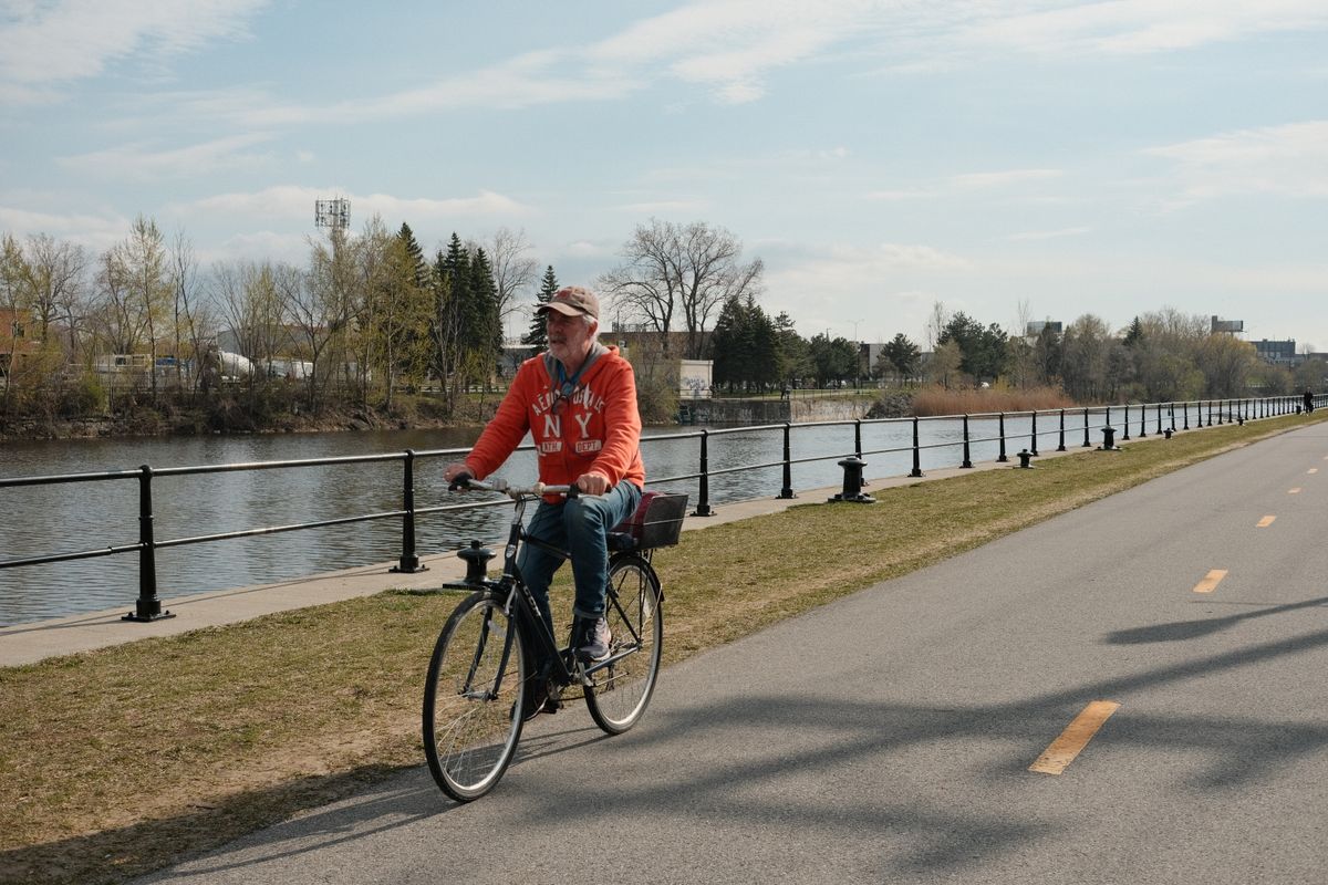 Older man riding a bicycle beside a riverside path