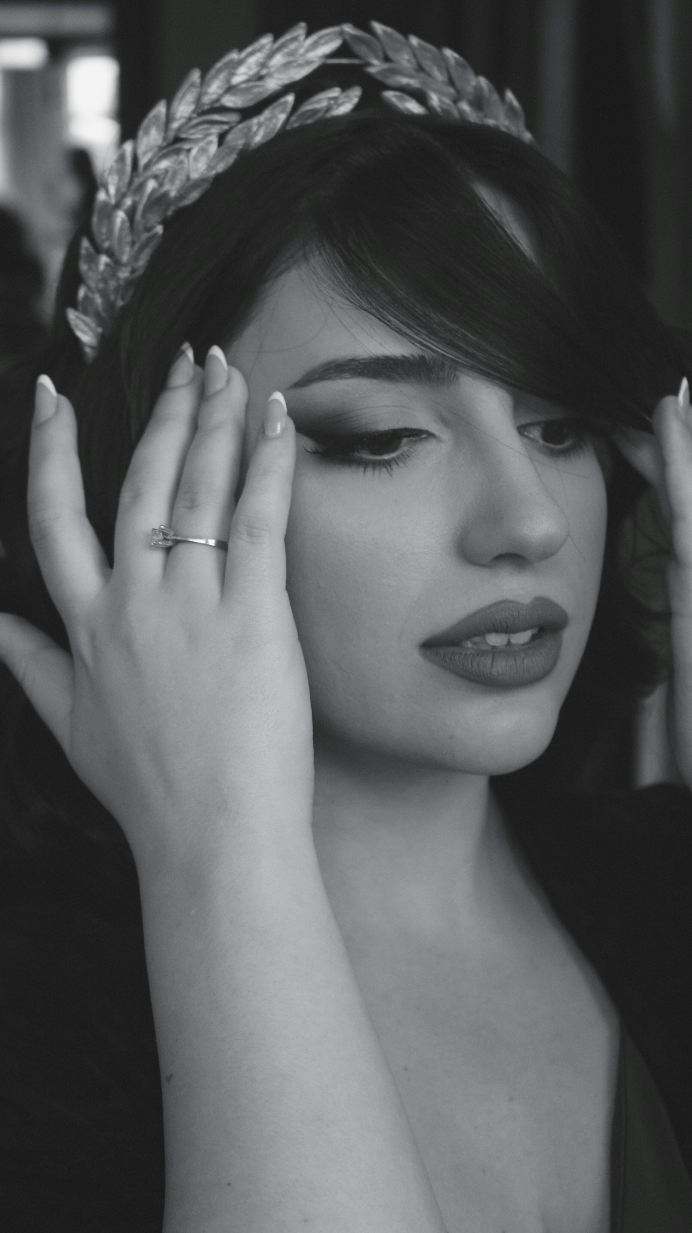 Artistic black and white portrait of a woman wearing a laurel wreath headpiece, highlighting her elegance and style.