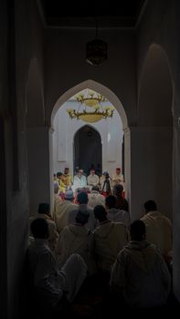 A group gathers for a spiritual ceremony inside a beautifully arched mosque interior.