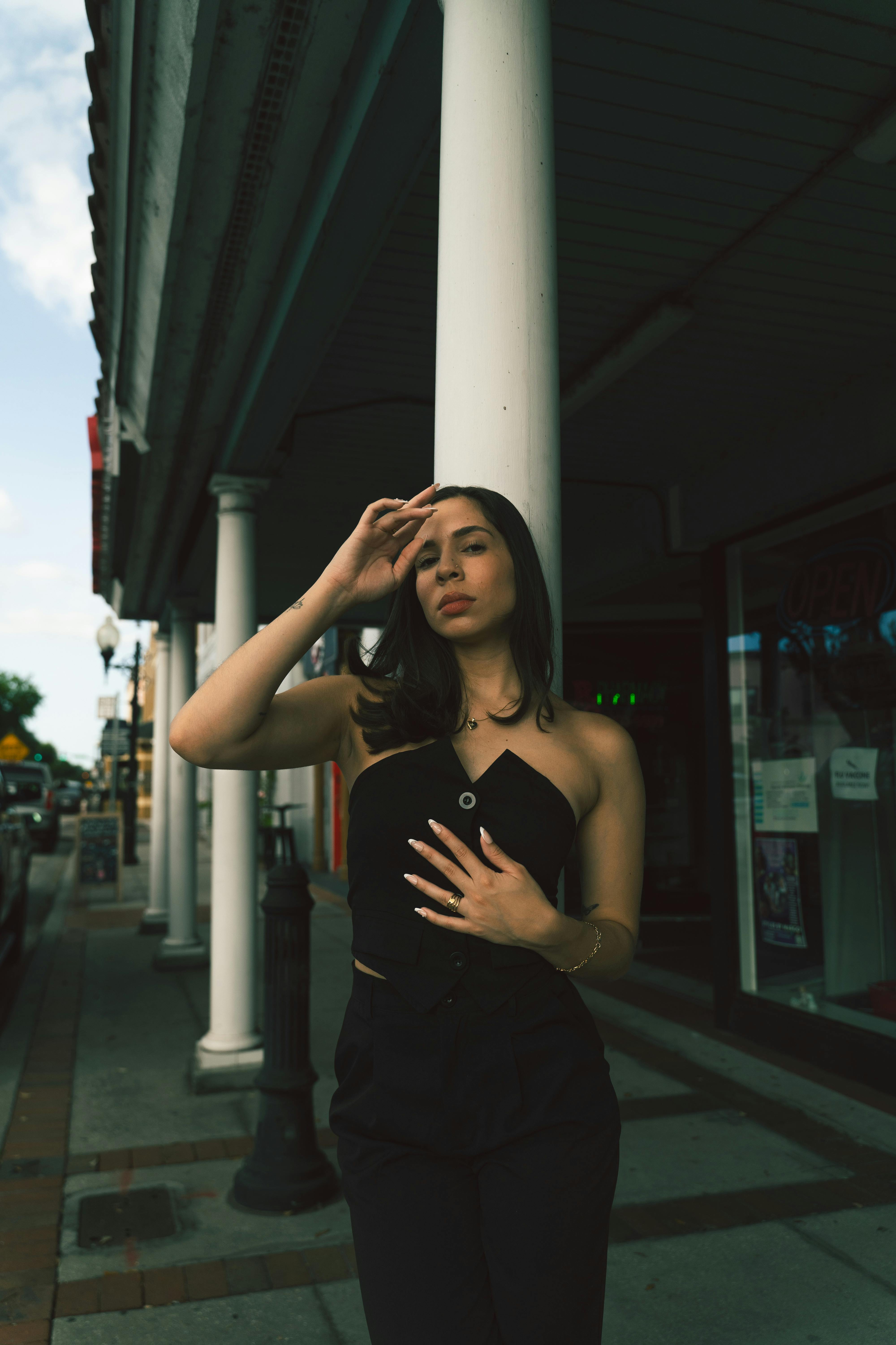 portrait of a stylish woman in black top and skirt standing in front of a column