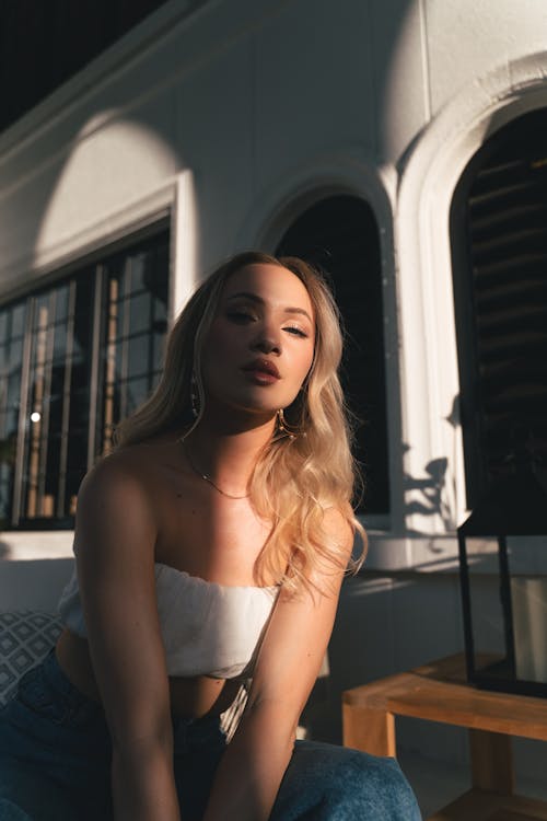 A woman in a white top and jeans sitting on a bench