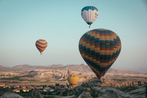Free Colorful hot air balloons gracefully soaring over Cappadocia's scenic landscape during a clear day. Stock Photo