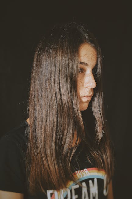 Portrait of a young woman with long straight hair, gazing to the side in a thoughtful pose.