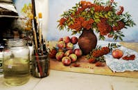 静物画中，一罐画笔放在苹果和浆果旁边