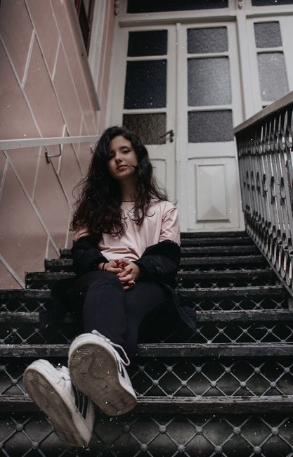 Young woman sitting on outdoor staircase with a serene expression in Teresópolis, Brazil.