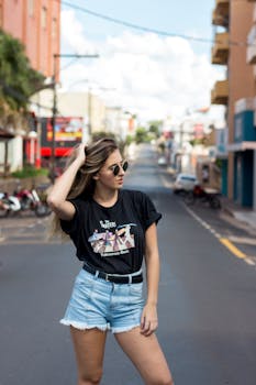一位时尚的年轻女子在阳光明媚的城市街道上摆出姿势，展现夏季的都市风尚