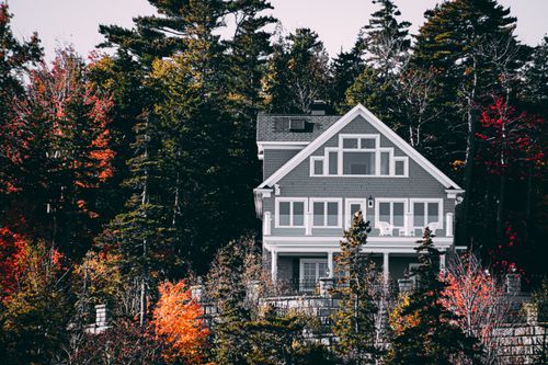 Free Elegant family home set against a vibrant autumn forest backdrop. Stock Photo