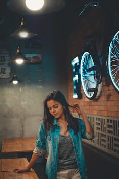 Portrait of a stylish young woman in a trendy denim jacket in a cozy urban restaurant setting.