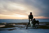 黄昏时分，白雪皑皑的海边，一位骑着摩托车的女人构成了一幅宁静的冬日图景