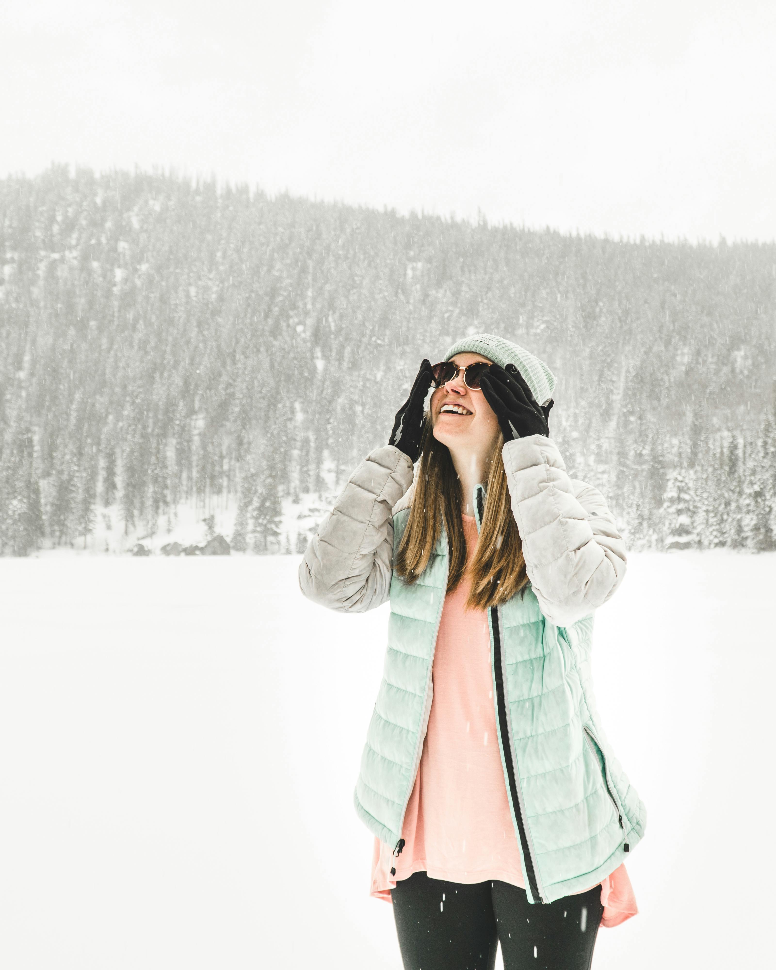 在科罗拉多埃斯蒂斯公园的森林里，一位穿着冬装的快乐女人正享受着下雪天