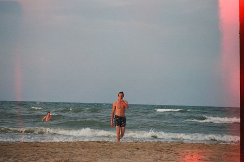 Free Two men enjoying a sunny day on a sandy beach by the ocean. Stock Photo