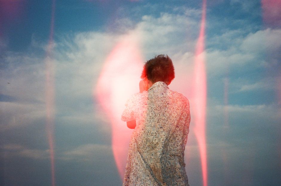 A creative back view portrait featuring a light leak effect in a bright outdoor setting.
