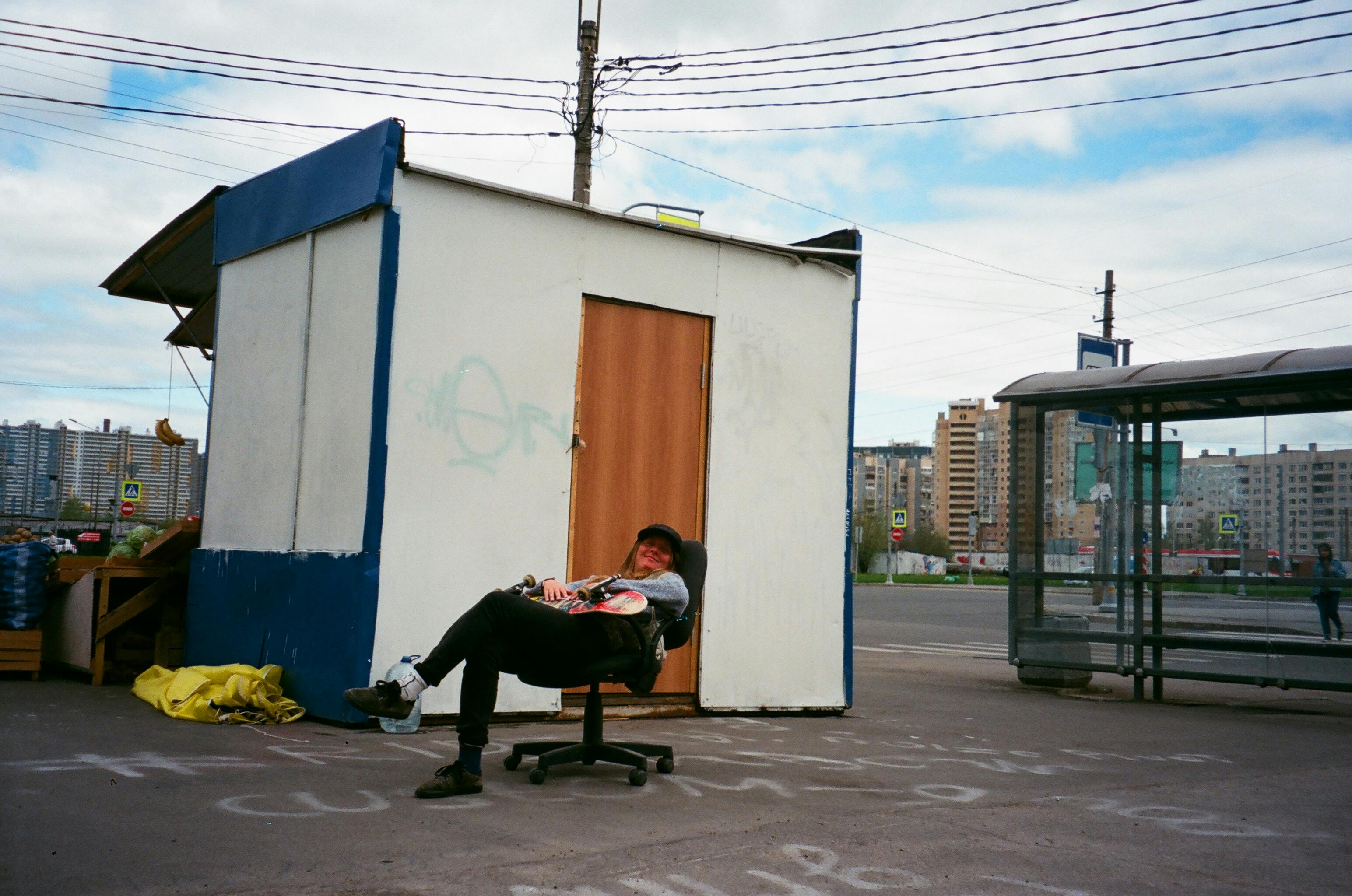 晴朗的日子里，一个男人在城市街边的摊位旁，坐在椅子上放松