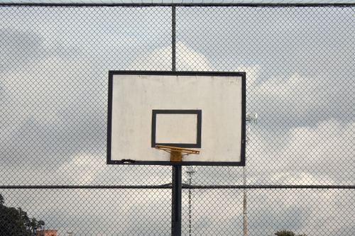 Free A solitary basketball hoop on an empty court with a cloudy sky background. Stock Photo