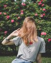 一位金发碧眼的女人在夏日花园里，充满活力地纹身，周围环绕着粉红色的花朵