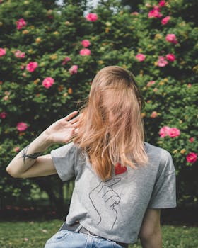 一位金发碧眼的女人在夏日花园里，充满活力地纹身，周围环绕着粉红色的花朵