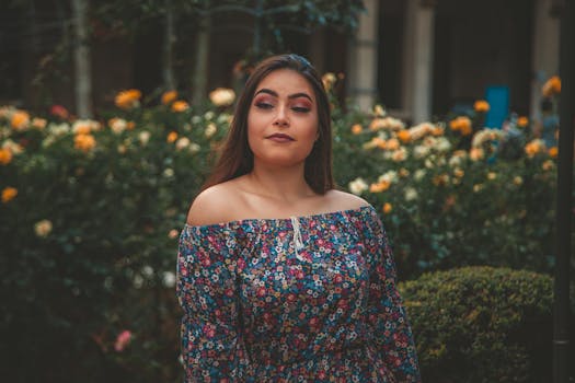 一位穿着花裙的女人在花丛中闭着眼睛摆姿势，表情安详