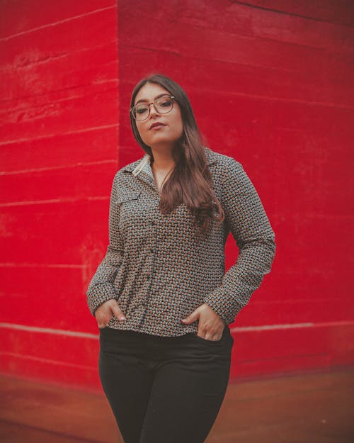 Photo of Standing Woman Posing In Front Of Red Building Wall