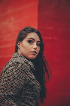 一位身着休闲服的女士，在充满活力的红色墙壁前优雅地摆姿势的肖像