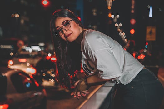 夜晚，城市灯光充满活力，一位长发黑发、戴着眼镜的女人正在摆姿势