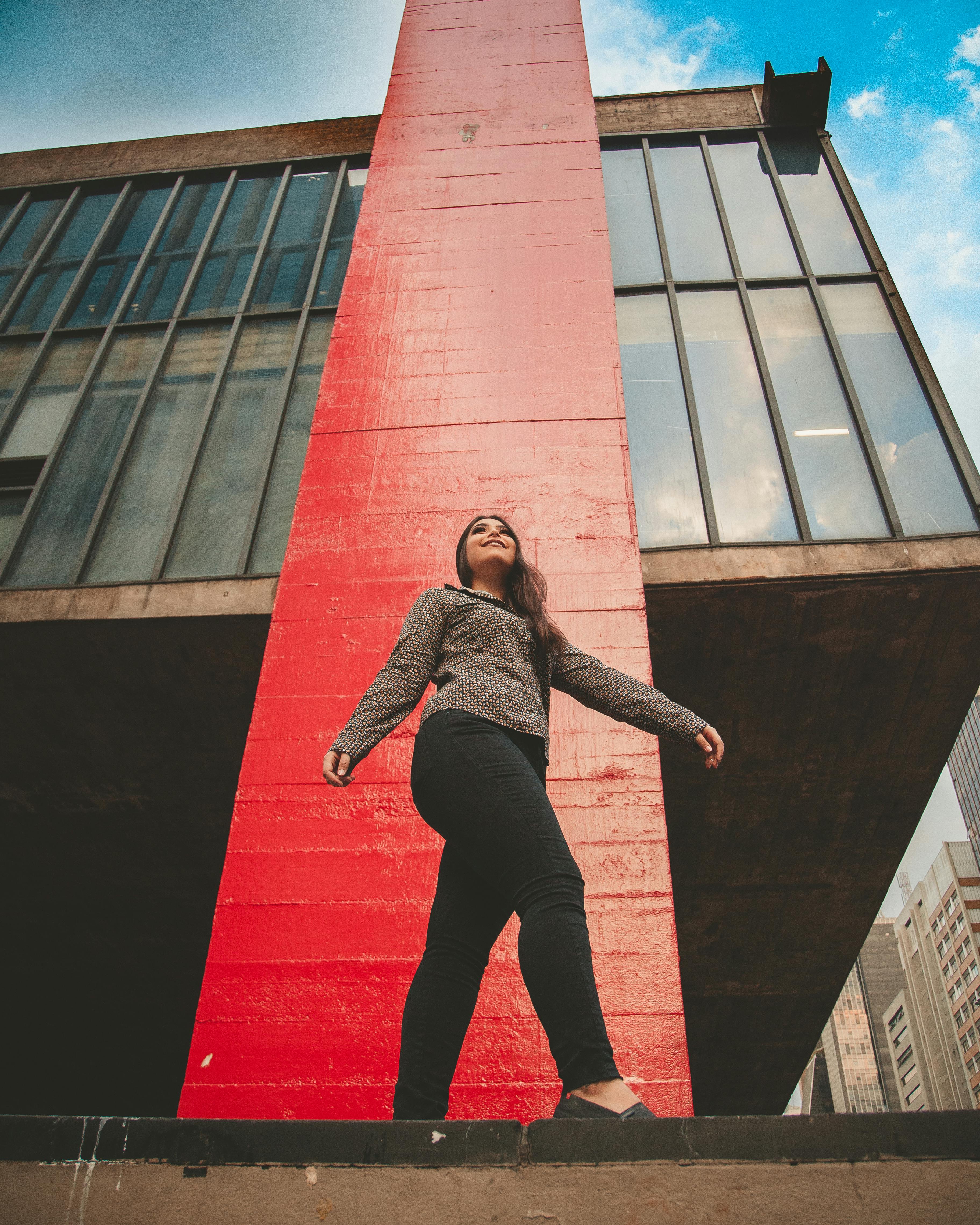 一位穿着休闲服的女士在现代城市建筑下自信地摆出姿势，展示着风格与设计