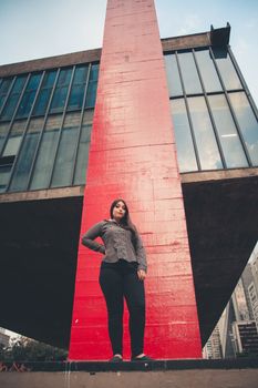 自信的女性在当代摩天大楼前摆出姿势，象征着赋权