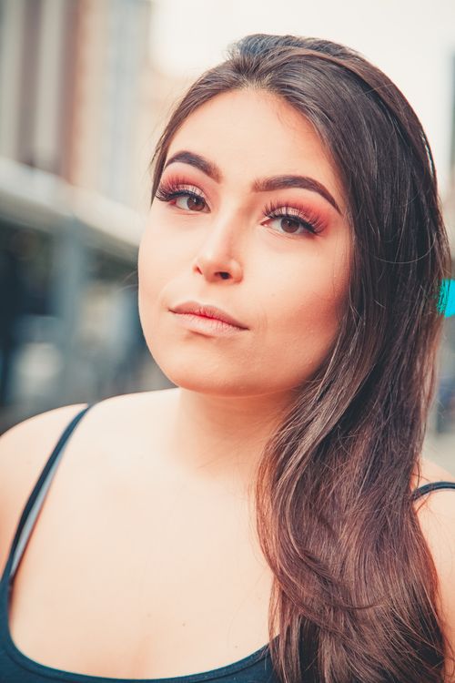 Free Close-up portrait of a young woman with long hair and subtle makeup, captured in an outdoor setting. Stock Photo